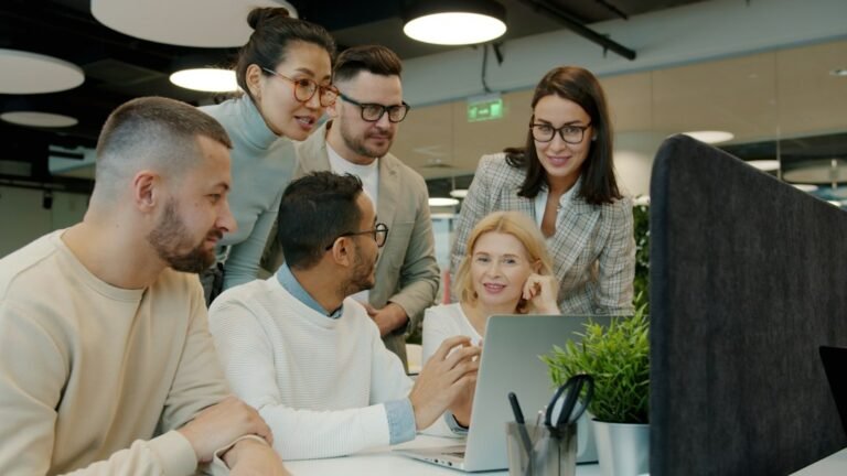 Young professionals collaborating around a laptop in a modern workplace