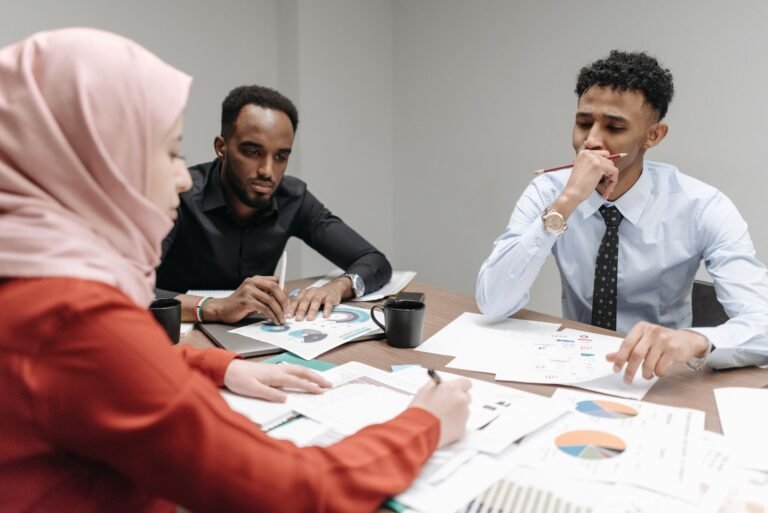 A diverse team of professionals engaged in a focused business meeting discussing documents and data.