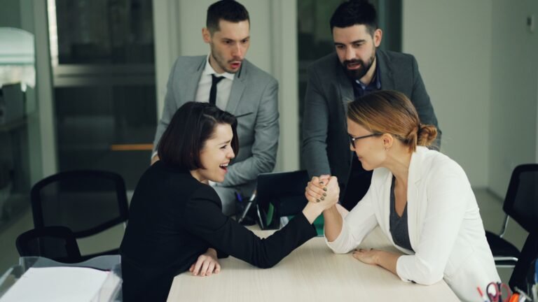 Colleagues engaging in a spirited arm wrestling contest at work, showcasing teamwork and competition.