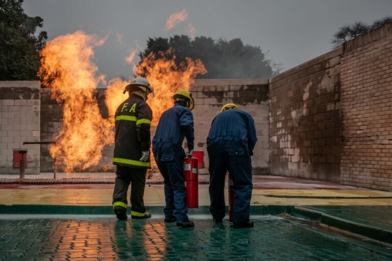 Group of firefighters in action using extinguisher during a training session with controlled fire.