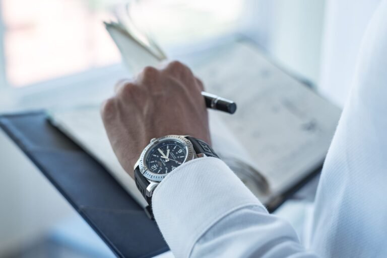Close-up of a wristwatch on a person's wrist while writing in a diary.