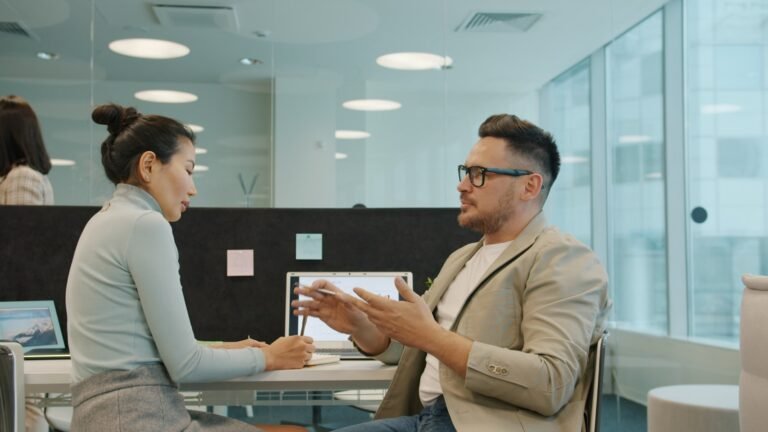 Two colleagues having a calm, resolution-focused discussion in a modern office