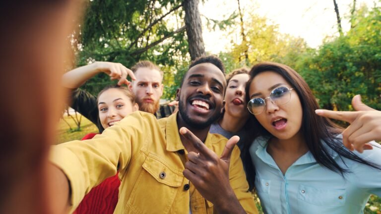 Group of diverse friends enjoying a playful selfie in a park setting.