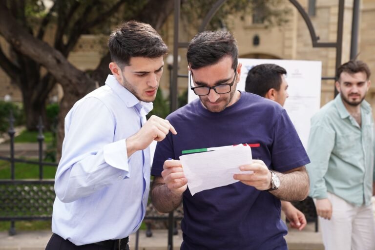 A group of adults engaged in discussion, analyzing documents outdoors in a park setting.