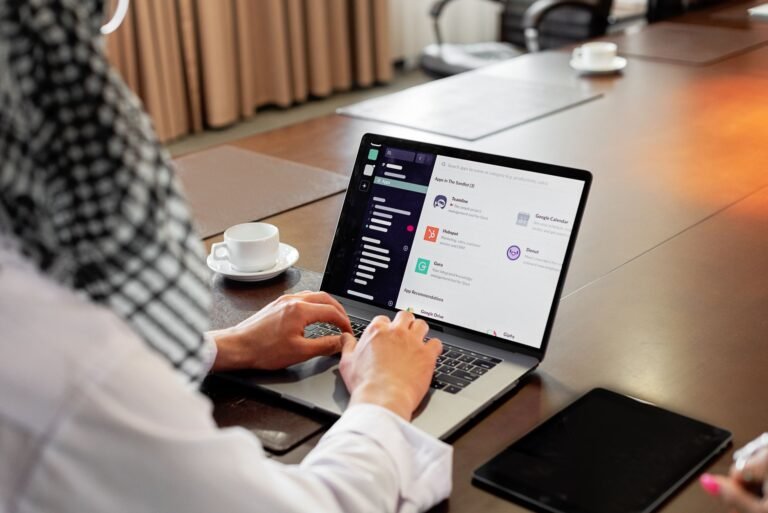Businessman using messaging app on laptop in modern office, engaging in team collaboration.