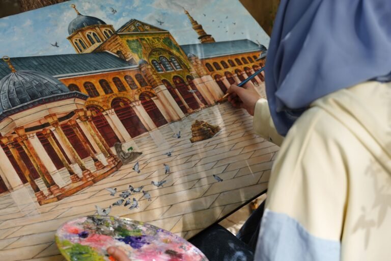 An artist paints the iconic Umayyad Mosque in Damascus while seated outdoors, capturing architectural details.